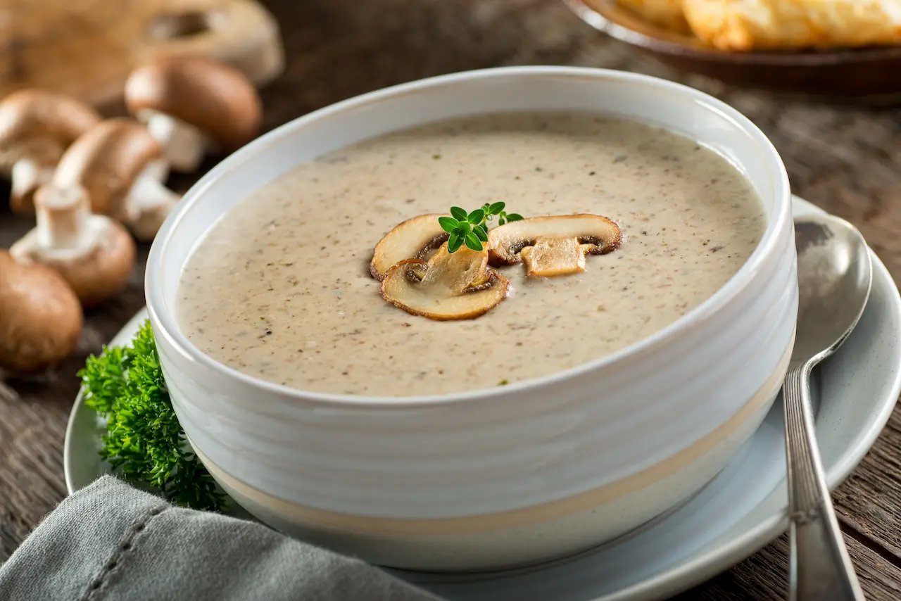 Cream of Mushroom Soup On a Plate Next to a Spoon