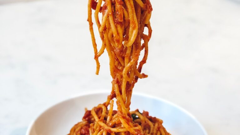 Bowl of cacio e pepe — bronze-die spaghetti glossy with Pecorino sauce and freshly cracked black pepper